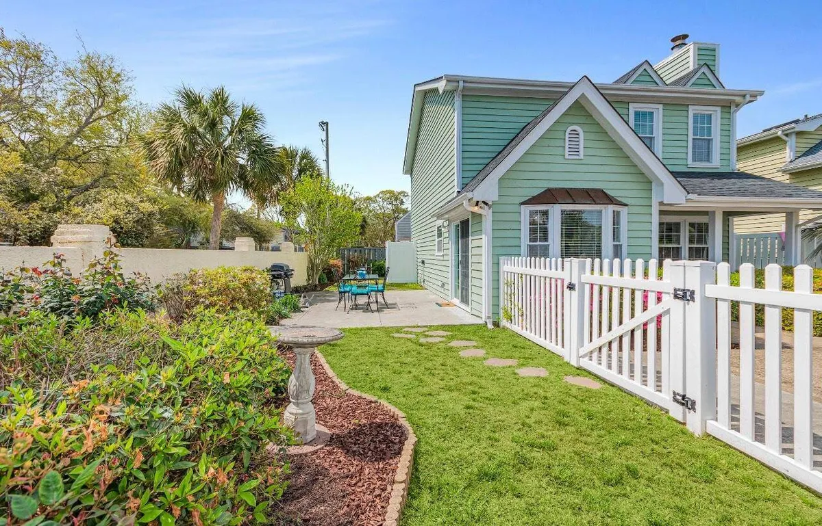 This image showcases the lush green exterior of the house, bordered by a charming white picket fence. There’s an outdoor seating area surrounded by vibrant garden greenery, creating an inviting space for gatherings and relaxation. The overall mood is cheerful and relaxed, perfect for families and pets to enjoy the outdoors safely.