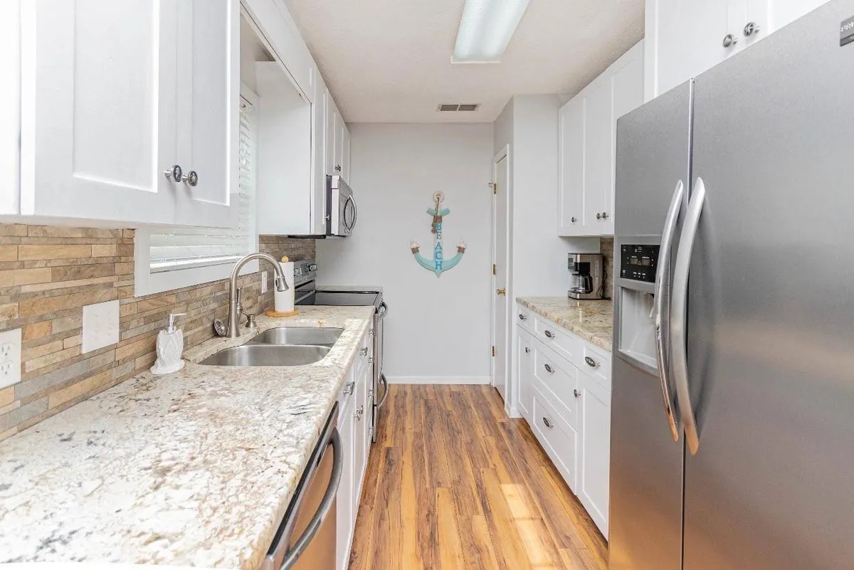 This image showcases a modern kitchen with granite countertops, stainless steel appliances, and a decorative anchor on the wall. The countertops gleam under warm lighting, and the space feels cozy yet functional, ready for group cooking and entertaining.