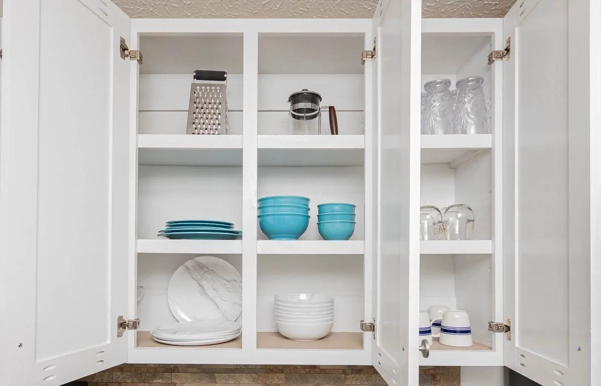 A bright kitchen scene with crisp white cabinetry, blue dishware, glassware, and culinary tools. The setup hints at both daily routines and special gatherings around food.